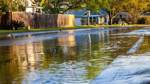 Street with water coving paving with building and fence onthe side