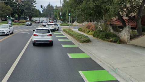 Car on paved rode next to green striped bike lane.png