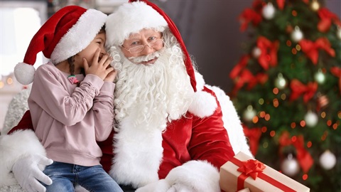 Little girl whispering and sitting on santa's lap (1).jpg