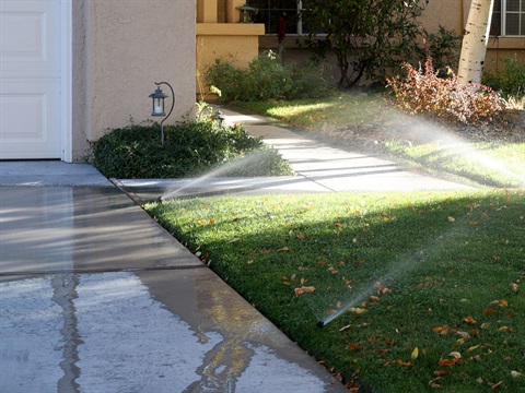 Lawn-sprinklers-overspray-and-runoff-onto-impervious-concrete-driveway-water-waste.jpg