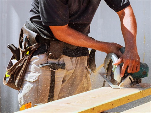 Man-uses-circular-saw-to-cut-wood-board.jpg