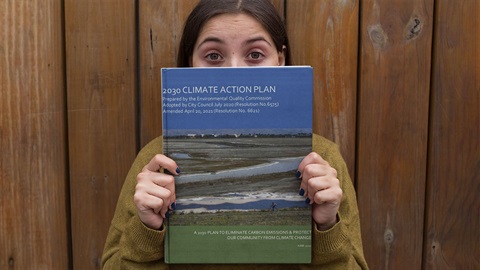 woman-holding-a-book-cover-of-the-2030-climate-action-plan-with-her-eyes-wide-open.jpg