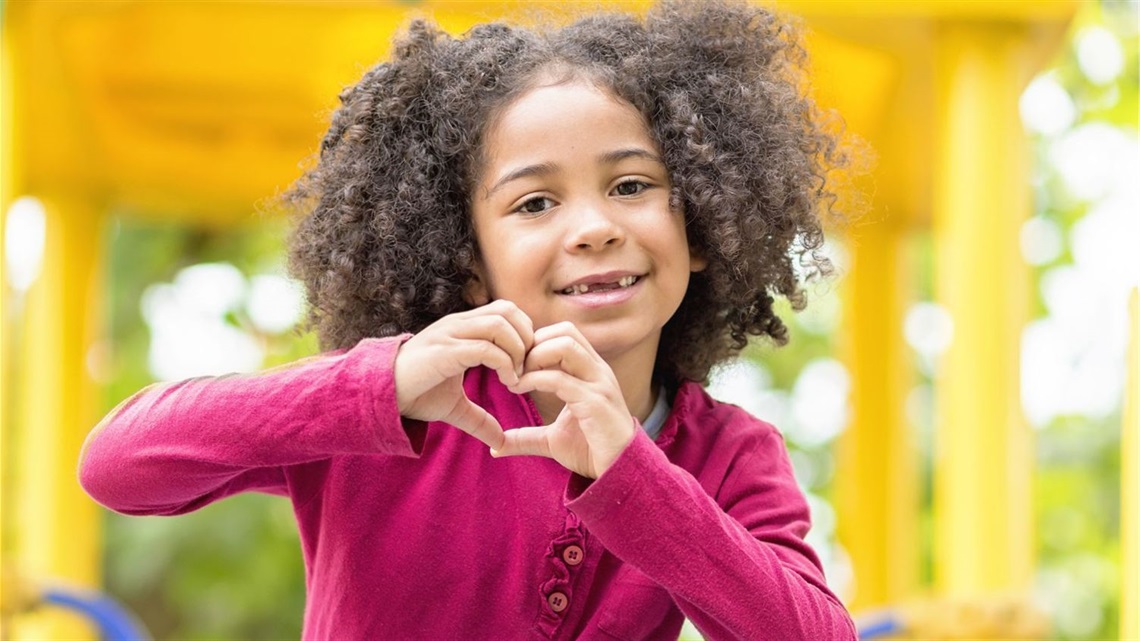 Black girl on playground putting her hands together in a heart.jpg