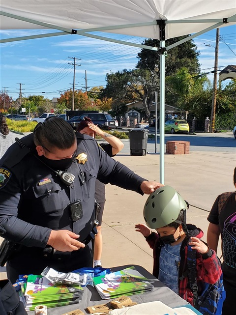 Officer fitting helmet on child at booth