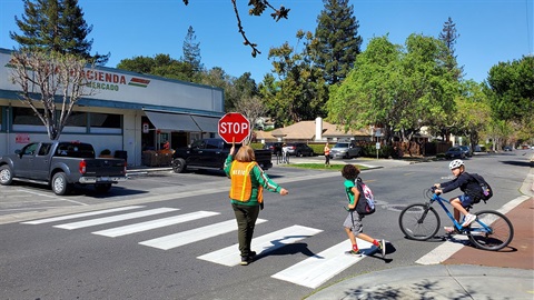 Crossing guard holding stop sign as children cross street