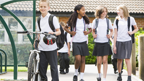 Children in uniforms with bike and walking with backpacks