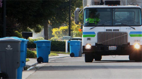 Garbage truck and recycling bins on street