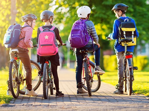 4-students-with-backpacks-pause-to-talk-while-riding-bicycles-to-school.jpg