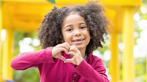 Black girl on playground putting hands together in a heart.jpg