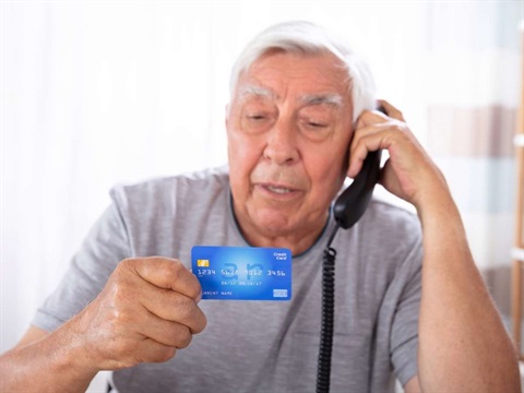 elderly hispanic man on phone holding credit card.jpg