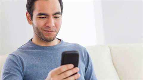 Man-sitting-on-couch-holding-smartphone.jpg