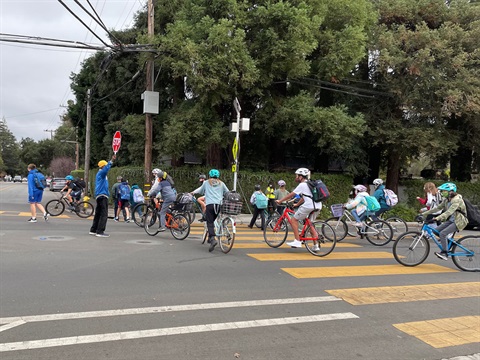 Student-bicyclists-cross-the-street-with-the-help-of-a-crossing-guard.jpg