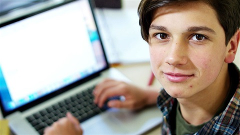 Teen looks at camera while using laptop.jpg