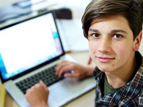 Teen-looks-at-the-camera-while-using-laptop.jpg