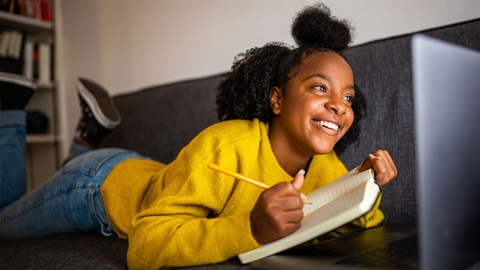 Teen writing in notebook while looking at laptop (1).jpg