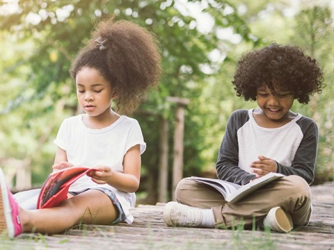 Two kids reading books outside.jpg