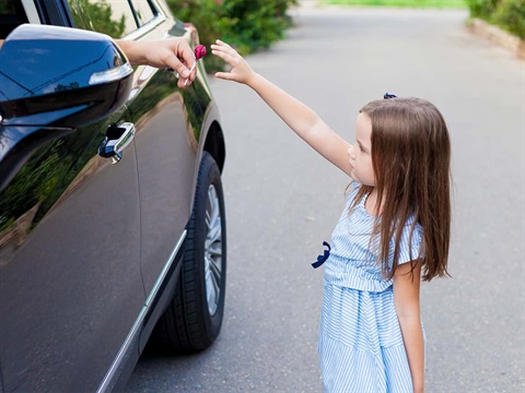 child-reaches-for-candy-handed-out-by-unknown-car-driver