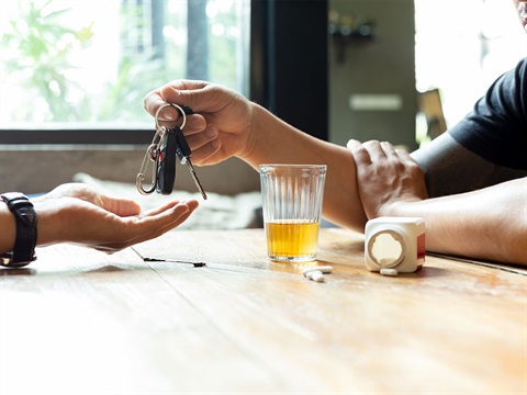 person-with-pills-and-alcohol-hands-over-car-keys.jpg