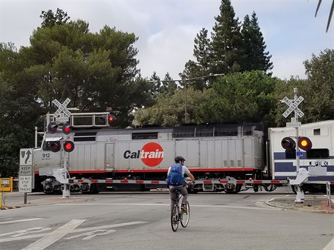 Bicyclist-stops-while-Caltrain-engine-passes-Ravenswood-Avenue-intersection.jpg