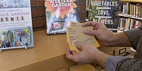 Hands holding seed packets in front of a re-purposed library card catalog